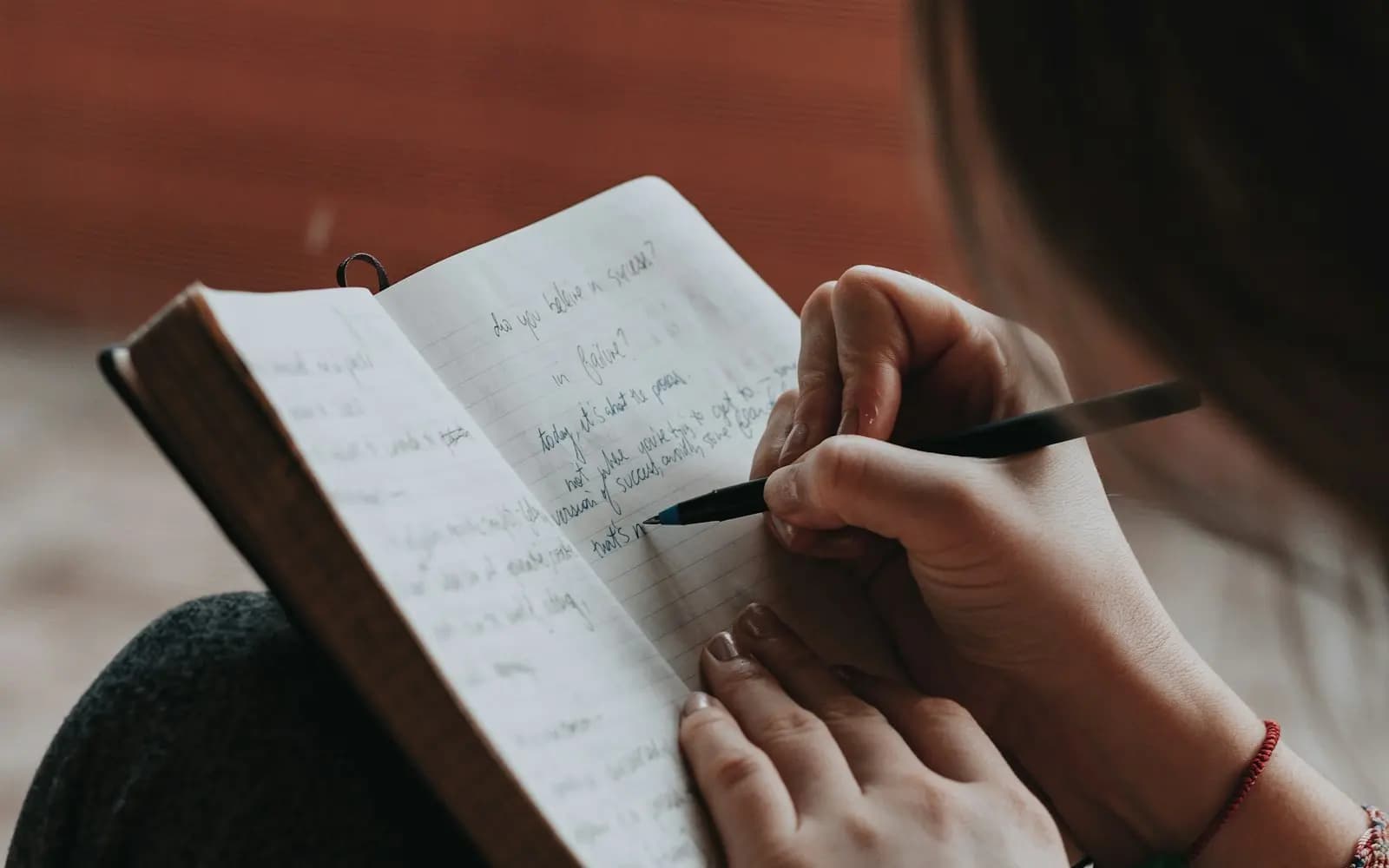 Someone writing notes by hand in an open notebook