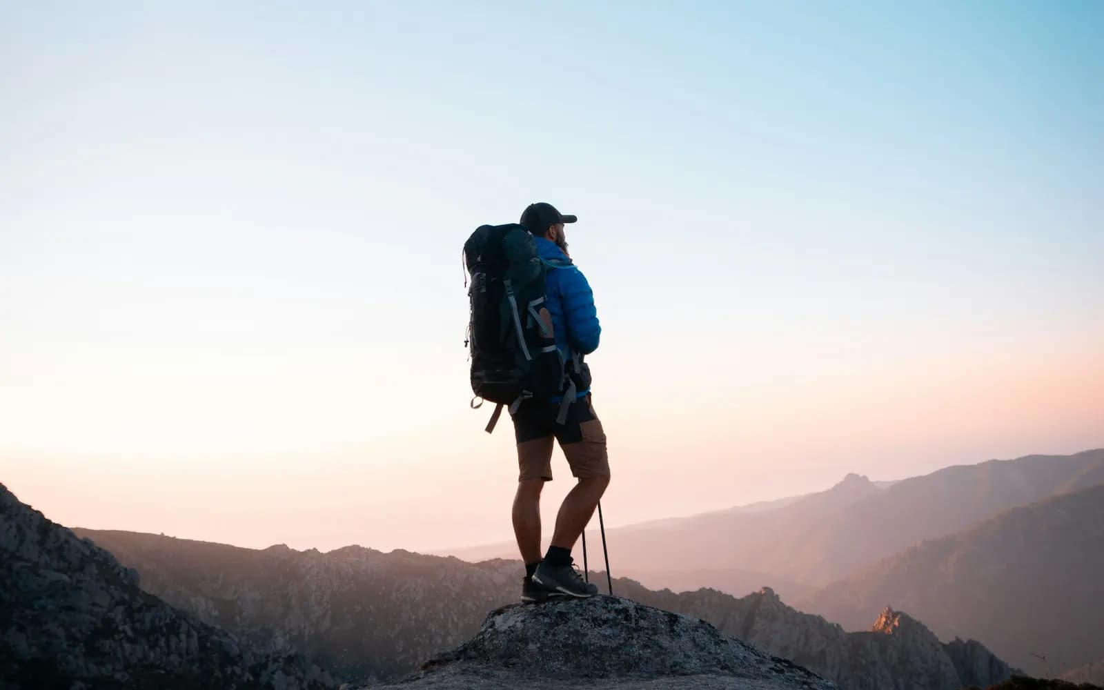 A hiker resting on a rocky ridge in warm golden-hour light